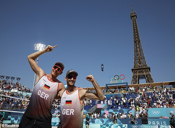 Paris 2024 Olympics - Beach Volleyball - Men's Preliminary Phase - Pool C - Germany vs France (Ehlers/Wickler vs Bassereau/Lyneel) - Eiffel Tower Stadium, Paris, France - July 30, 2024. Nils Ehlers of Germany and Clemens Wickler of Germany pose for a picture after winning, with the Eiffel Tower and Olympic rings in the background. REUTERS/Louisa Gouliamaki