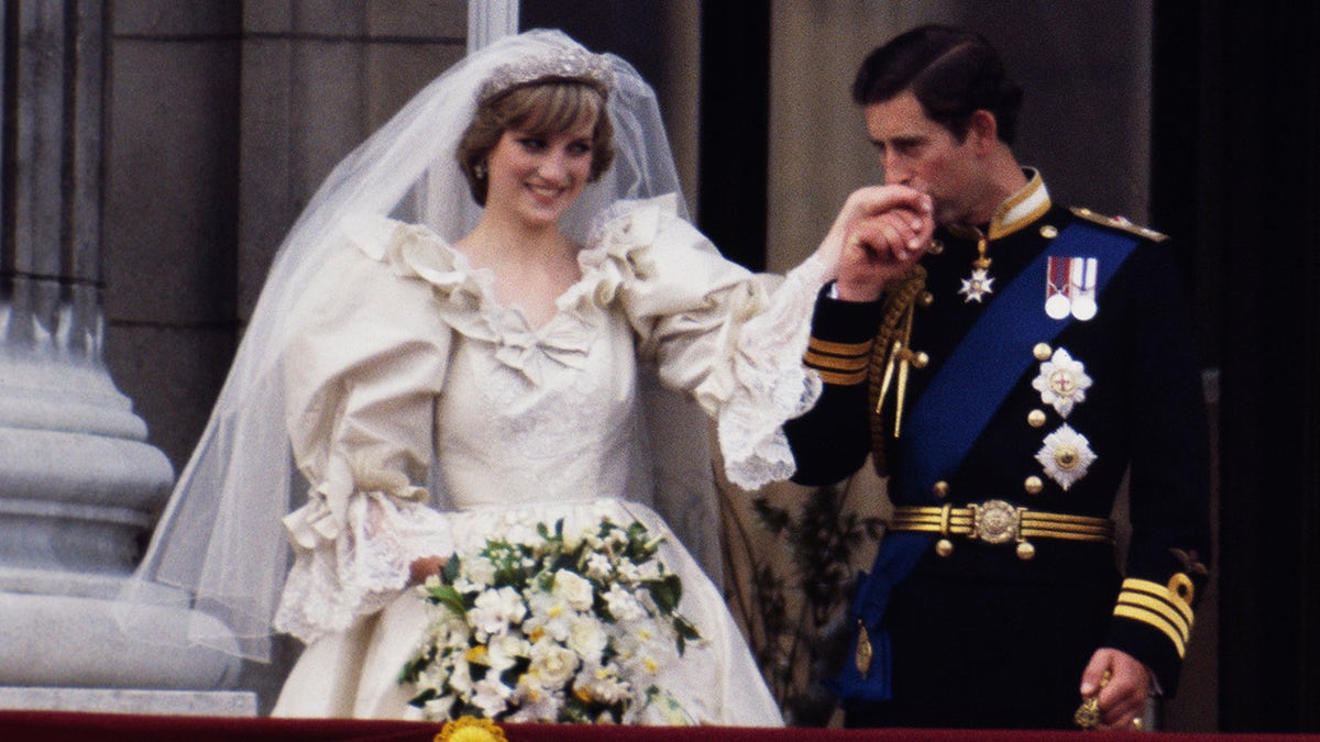 Prince Charles kissing Princess Diana's hand on their wedding day.