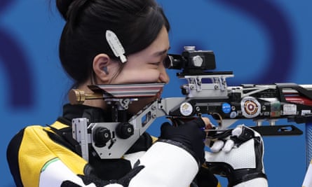 Woman in yellow, white and black uniform aims air rifle