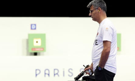 Yusuf Dikeç holds a pistol in one hand and has his other in his pocket