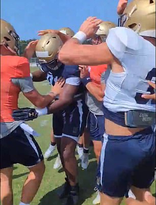 The Navy football player is mobbed by his teammates