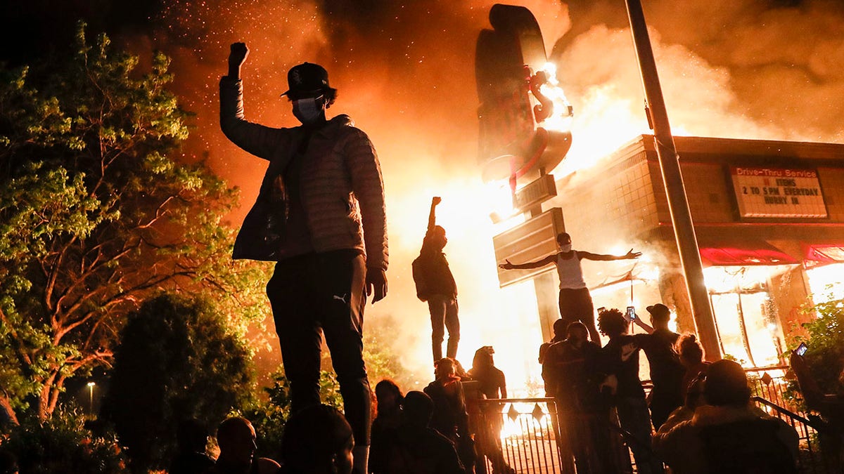 Protesters gather outside a fast-food restaurant ablaze, Friday, May 29, 2020, in Minneapolis.