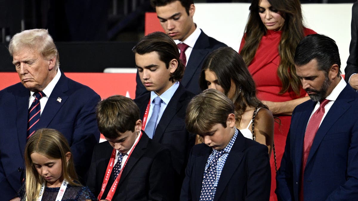 US former President and 2024 Republican presidential candidate Donald Trump bows in prayer alongside his grandchildren during the third day of the 2024 Republican National Convention at the Fiserv Forum in Milwaukee, Wisconsin, on July 17, 2024. Days after he survived an assassination attempt, Donald Trump won formal nomination as the Republican presidential candidate and picked Ohio US Senator J.D. Vance for running mate. (Photo by Brendan SMIALOWSKI / AFP)