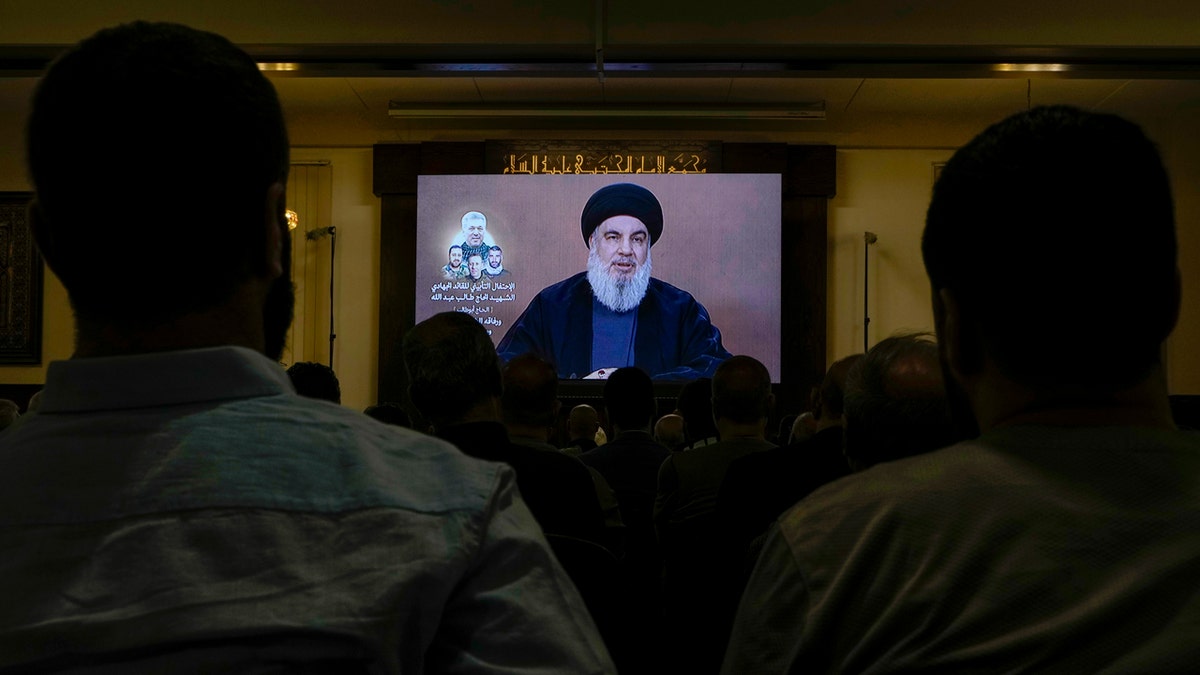 Hezbollah supporters watching a speech given by Hezbollah leader Sayyed Hassan Nasrallah on a screen.