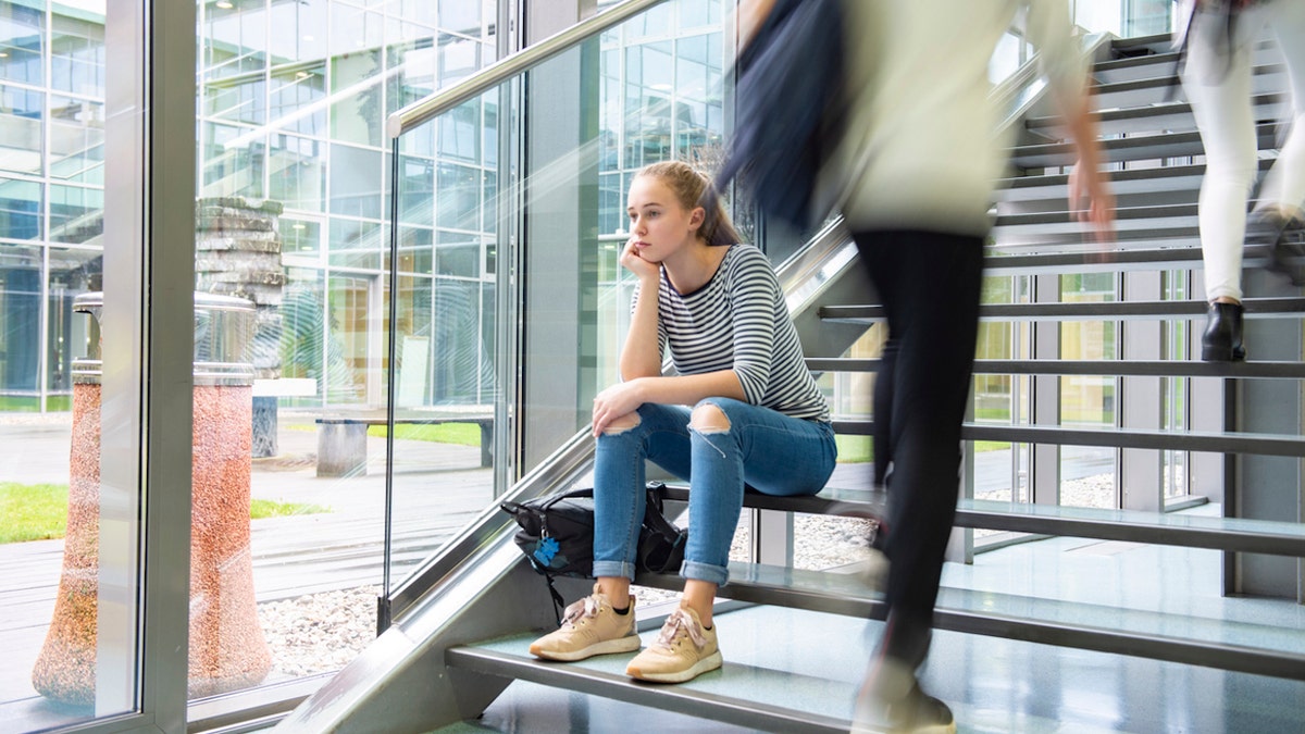 Sad girl sitting on staircase.